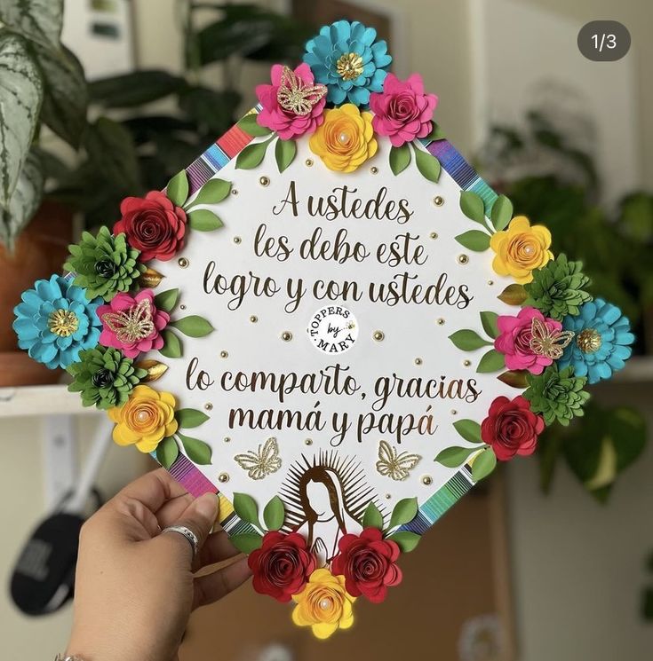 a person holding up a paper cutout with flowers on it and the words written in spanish