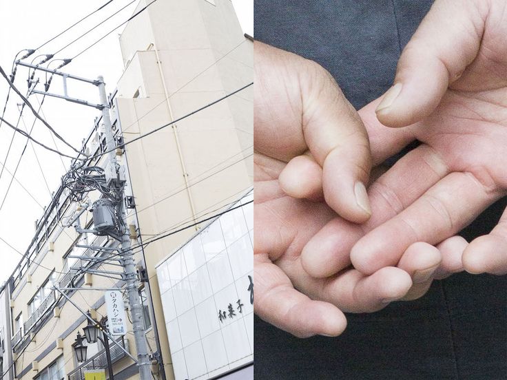 two hands holding something in front of a building and power lines on the other side