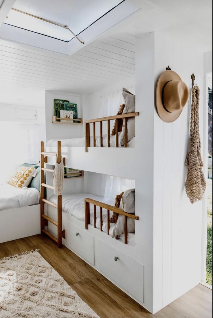 a bedroom with bunk beds and white walls, wooden floors and hanging items on the wall