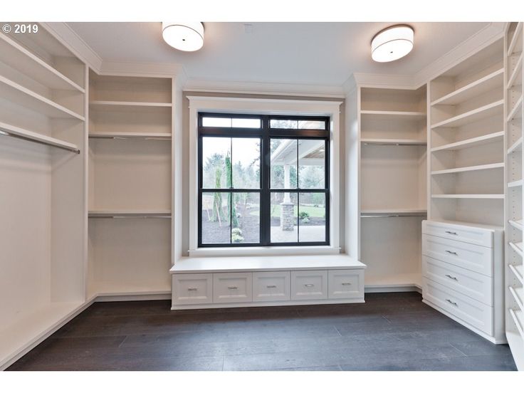 an empty walk in closet with lots of white shelving and drawers on the walls