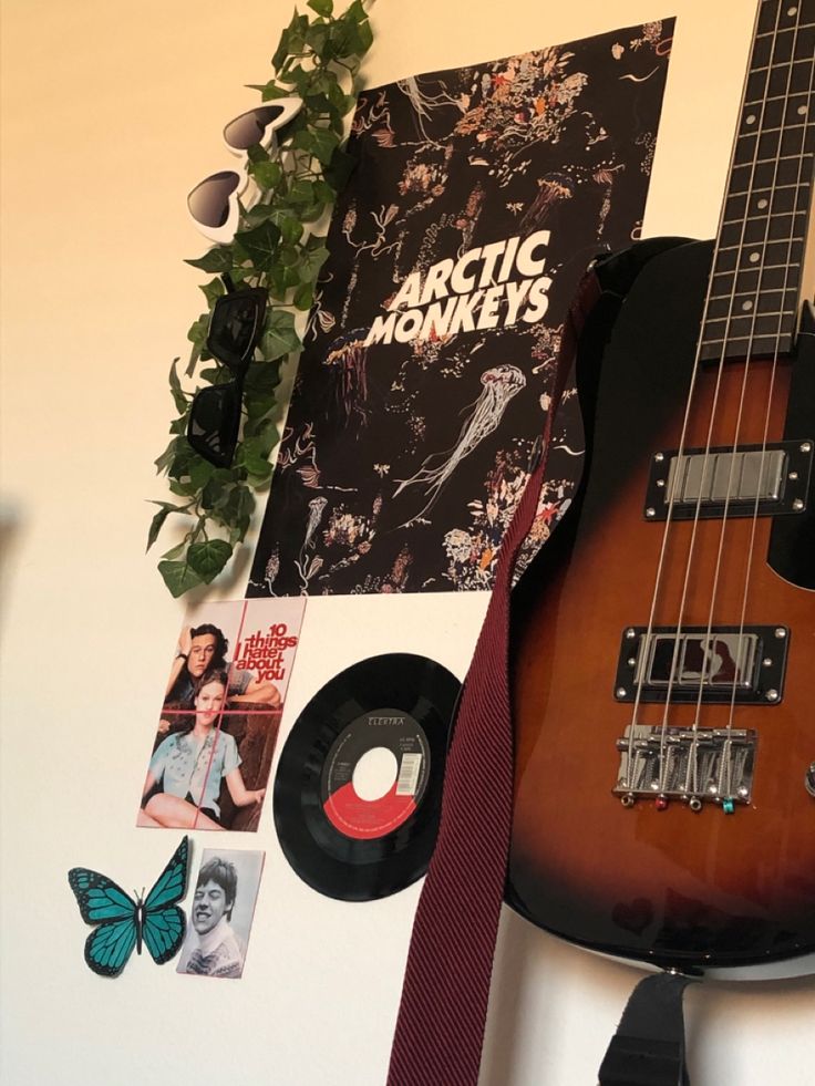 an electric guitar is hanging on the wall next to some pictures and a potted plant