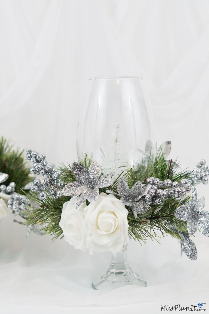 a glass vase filled with white flowers and greenery