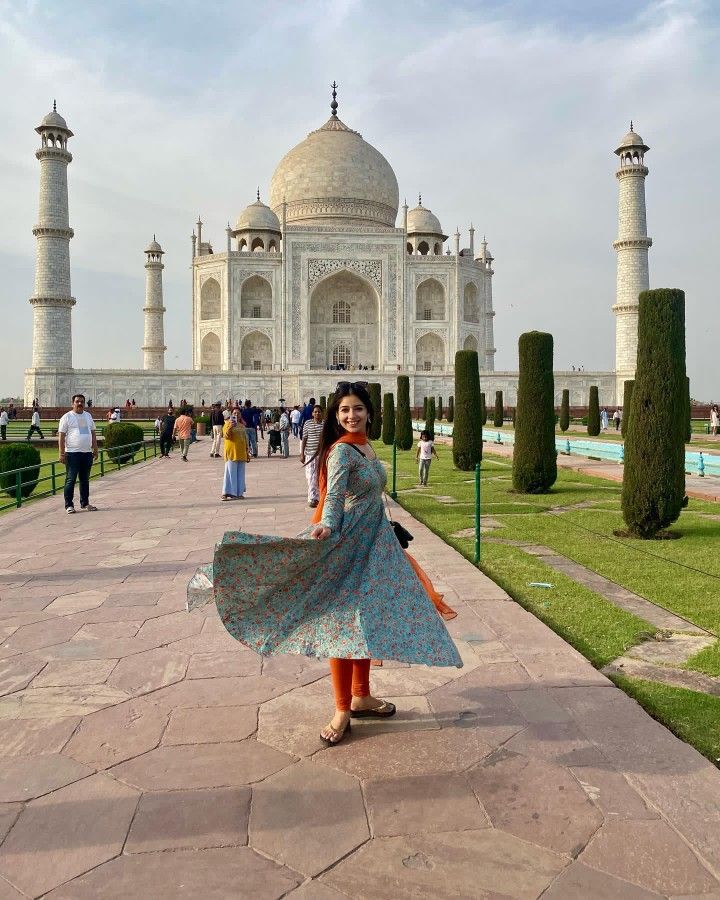 a woman standing in front of the tajwa mosque, with her dress blowing in the wind