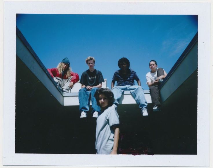 four young men sitting on the edge of an escalator