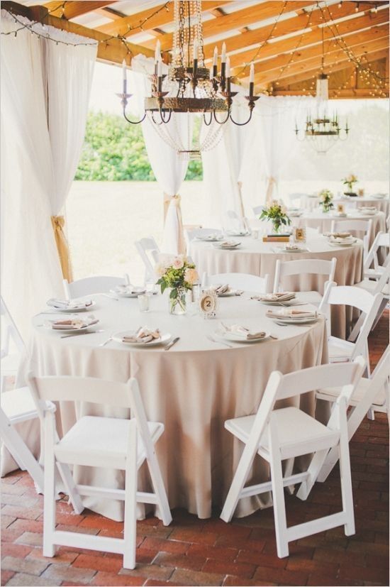 a table set up for a wedding with white chairs and chandelier hanging from the ceiling