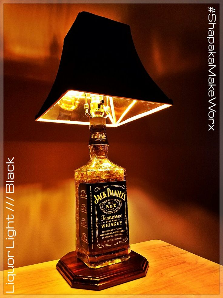 a lamp that is sitting on top of a table with a bottle in front of it