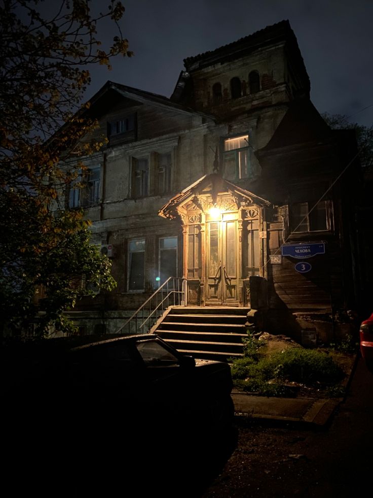 an old house lit up at night with its lights on and stairs leading to the front door