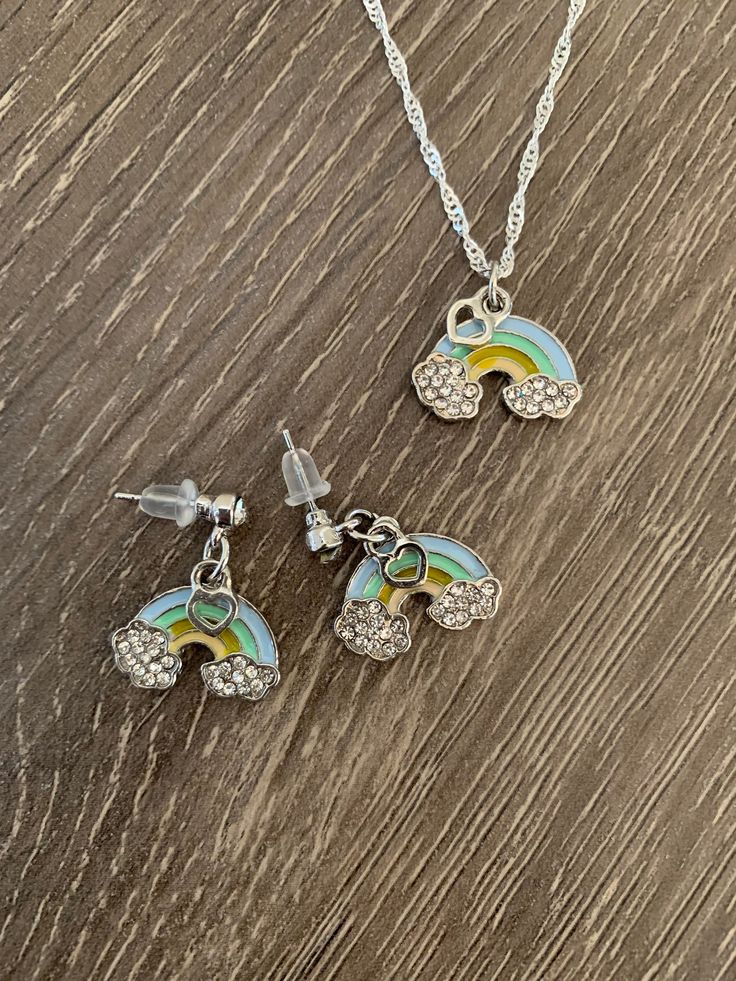 These little rainbows are so Cute! Your choice of Rainbow Earrings, Necklace or Both Rainbow enamel painted charm with tiny dangling heart charm. Earings are on a crystal stud. Comes on high quality short chain necklace. Come packaged in a cellophane bag with Baptism Themed Rainbow Card Rainbow Metal Jewelry With Adjustable Chain, Rainbow Hypoallergenic Jewelry For Birthdays, Rainbow Hypoallergenic Jewelry For Birthday, Hypoallergenic Rainbow Colored Metal Jewelry, Hypoallergenic Rainbow Metal Jewelry, Rainbow Hypoallergenic Dangle Jewelry, Hypoallergenic Rainbow Dangle Jewelry, Cute Nickel-free Rainbow Jewelry, Multicolor Jewelry With Matching Earrings For Birthday