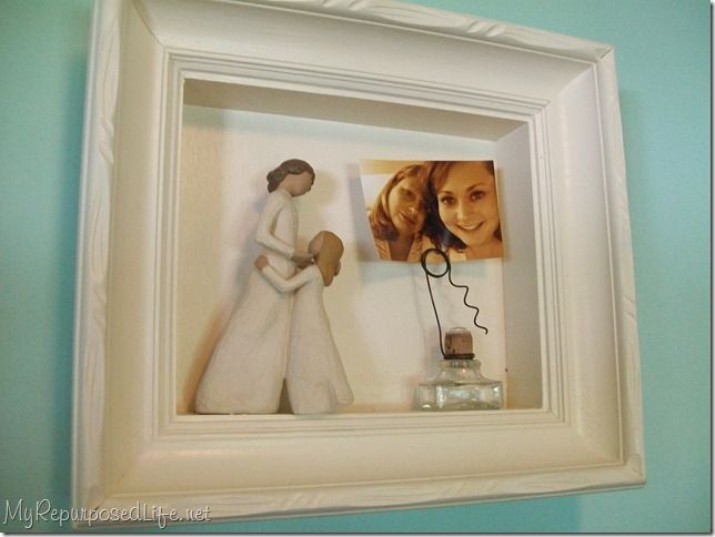 a white frame holding a couple figurines in it