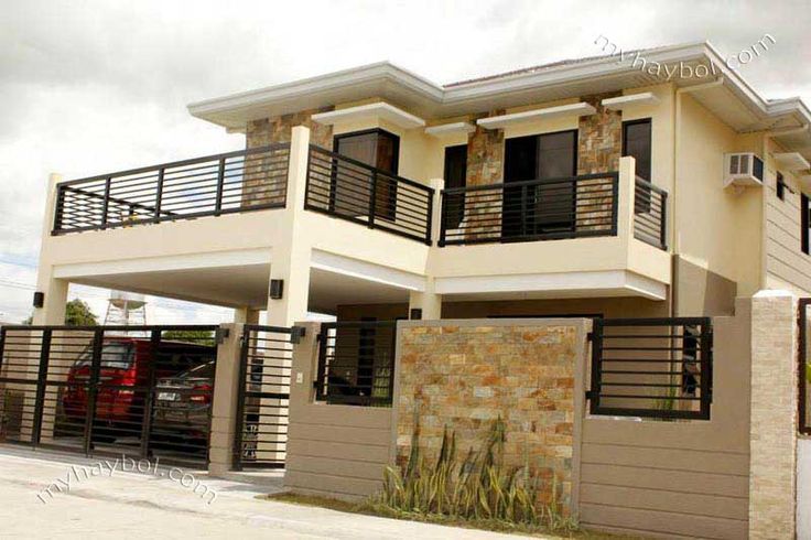 a two story house with a car parked in the driveway and balcony railings on each level