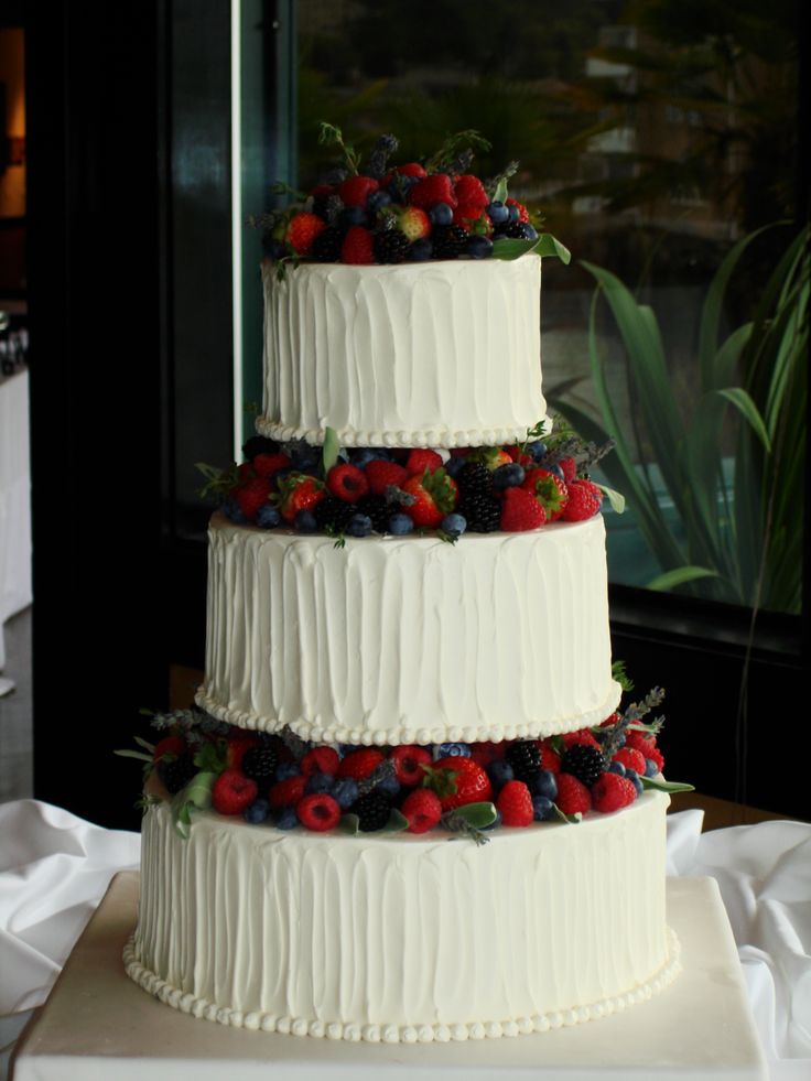 a three tiered cake with fresh berries on top