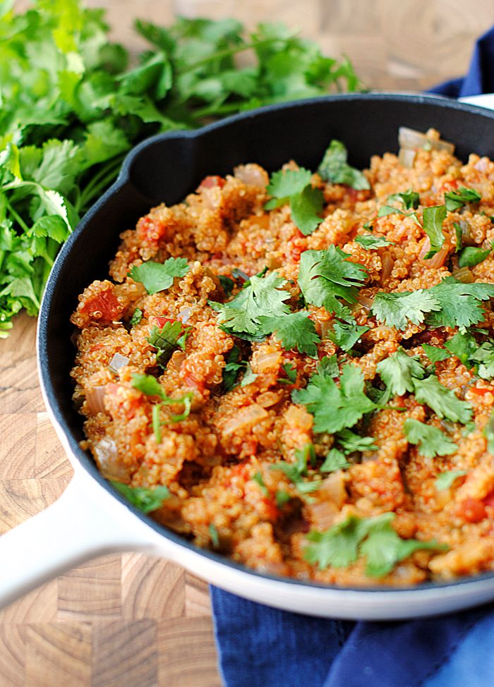 a pan filled with meat and cilantro on top of a wooden table