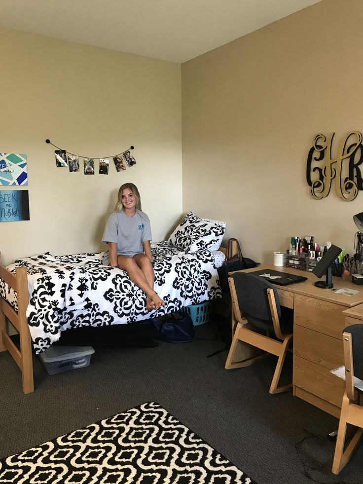 a woman sitting on top of a bed in a bedroom next to a desk and chair