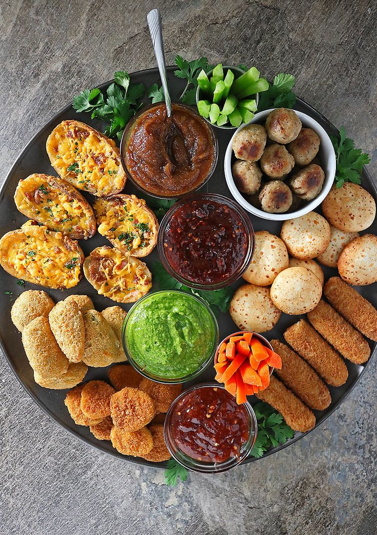 a platter filled with different types of food and dipping sauces on top of it