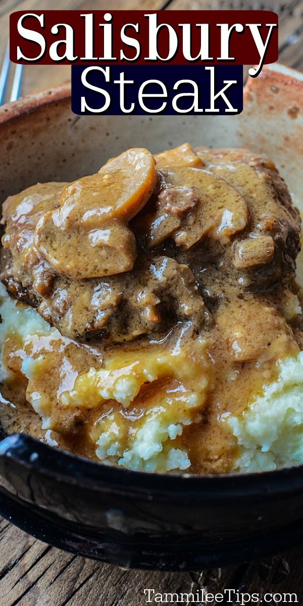 a bowl filled with meat and potatoes covered in gravy on top of a wooden table