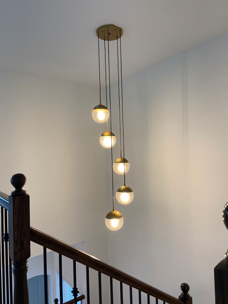 a chandelier hanging from the top of a stair case with five lights on it