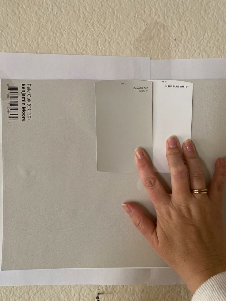 a person's hand on top of a piece of paper with some white paint