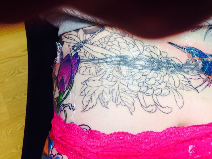 a woman's stomach covered in tattoos with flowers and birds on the top of it