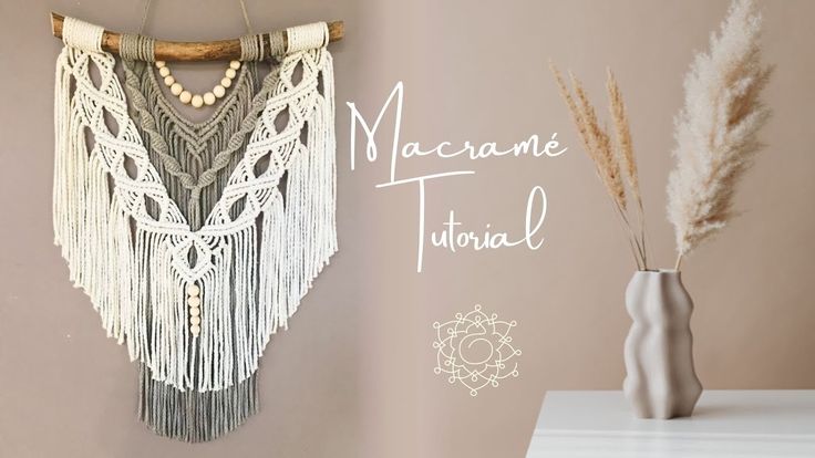 there is a vase with some flowers in it next to a macrame wall hanging