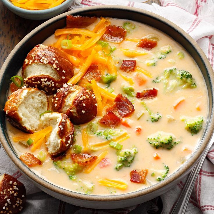 a bowl of soup with broccoli, cheese and other toppings on the side