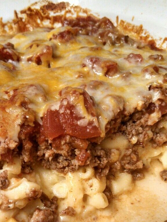 a white plate topped with lasagna covered in cheese and meat sauce on top of it