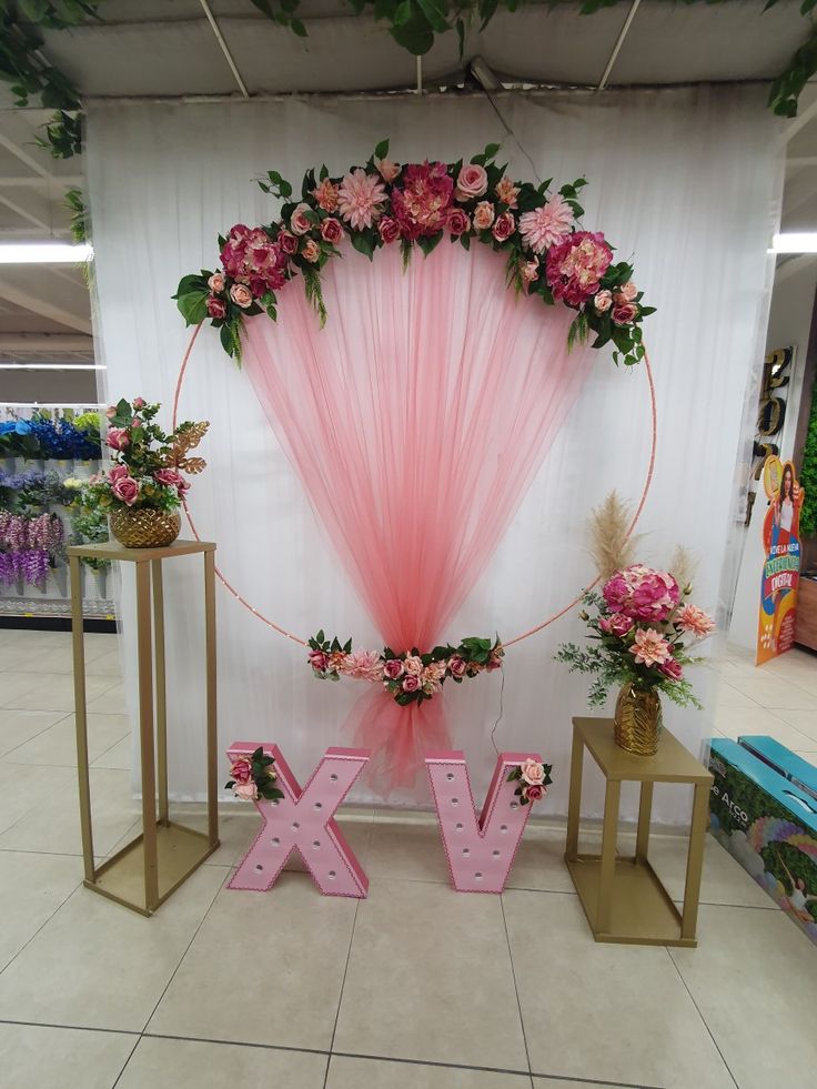 a pink backdrop with flowers and letters on the floor next to two small stools