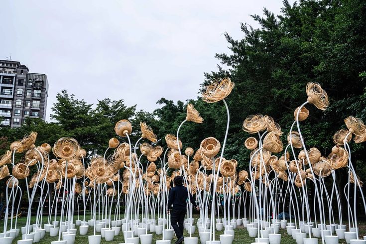 a man standing in front of an array of white vases with gold flowers on them