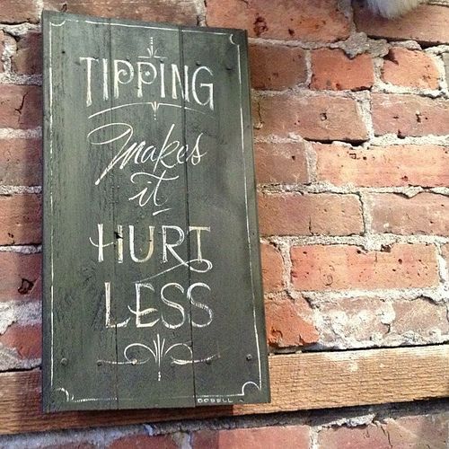 a sign that is on the side of a brick wall saying tipping makes a hurt less