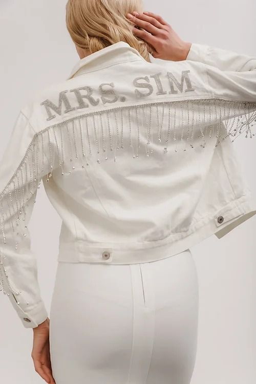 a woman wearing white pants and a jacket with the word mrs s m on it