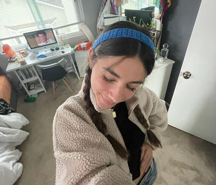 a girl in a room looking down at her cell phone while wearing a blue headband