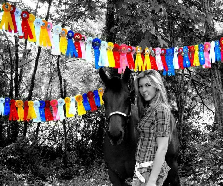 a woman standing next to a horse in front of a colorful streamer with clothes on it