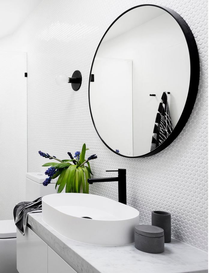 a white bathroom with a round mirror above the sink