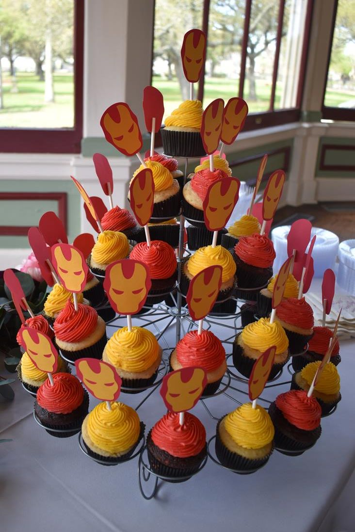 cupcakes with red and yellow frosting are arranged on a table