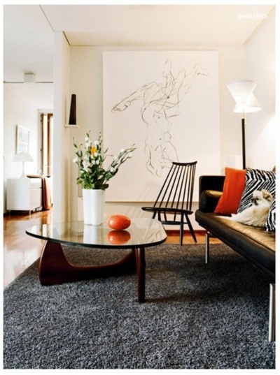 a living room filled with furniture and a large painting on the wall above it's coffee table