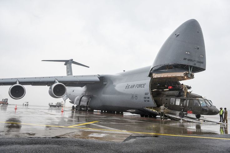 an airplane is parked on the tarmac with its cargo compartment open and people standing around it