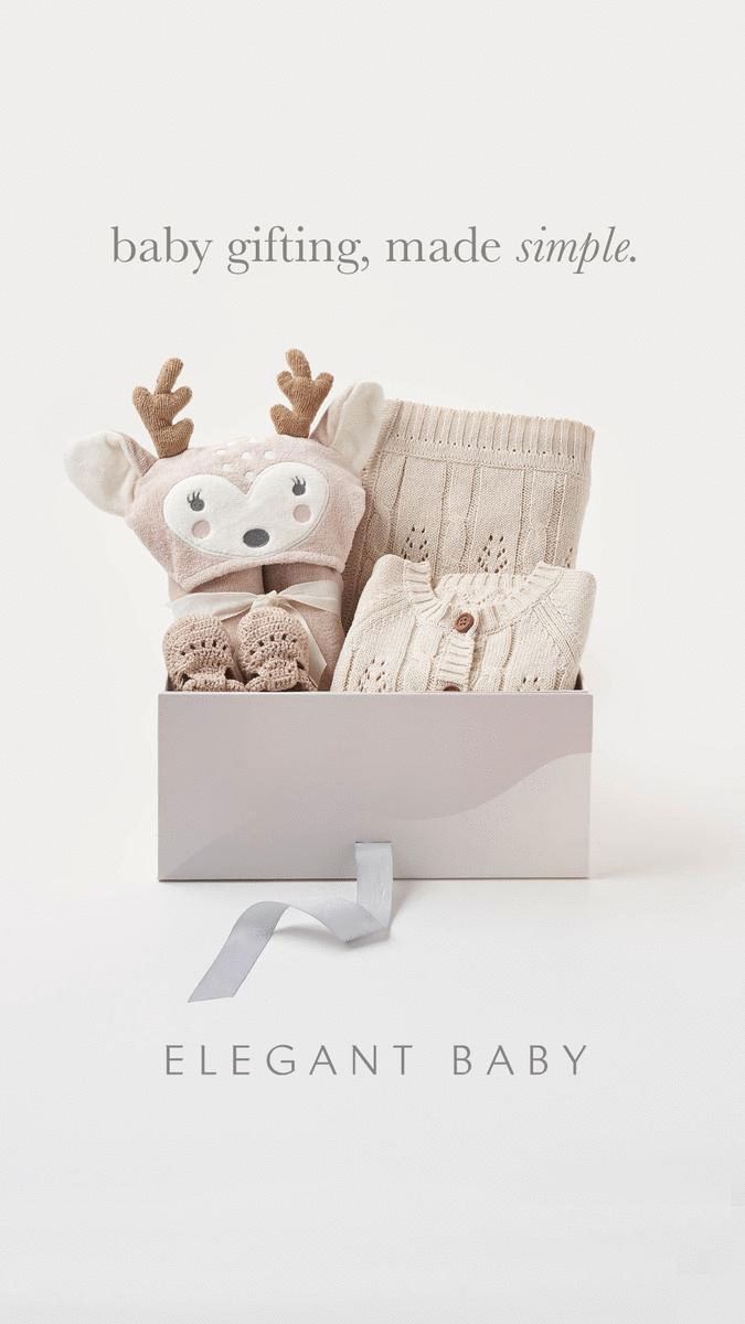 a baby's gift box with a stuffed animal and knitted clothes in it