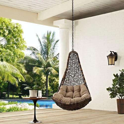 a hanging chair on a porch next to a table and potted plant in front of a pool