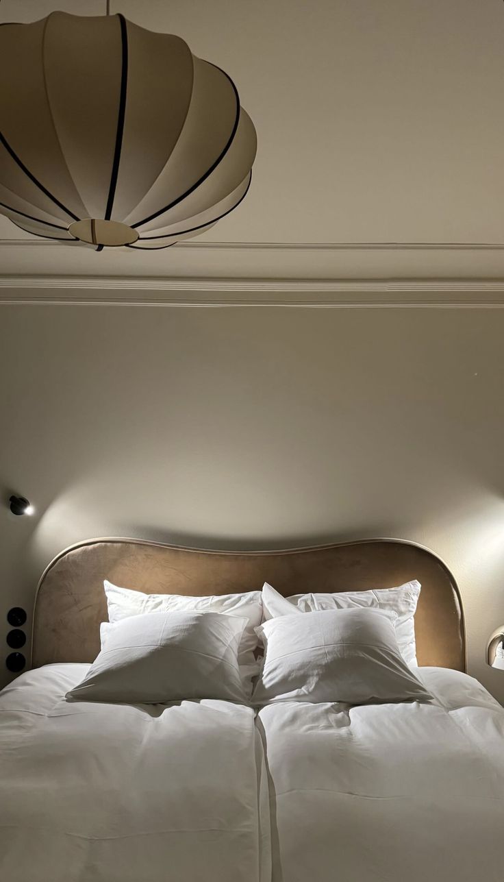 a bed with white sheets and pillows in a room