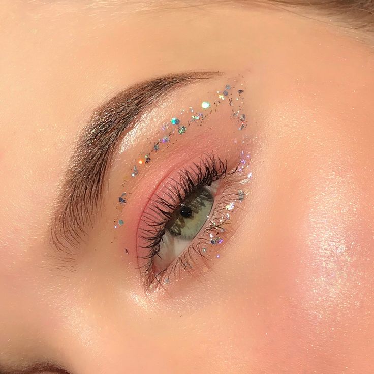 a woman's eye with glitters on her lashes and pink eyeshadow