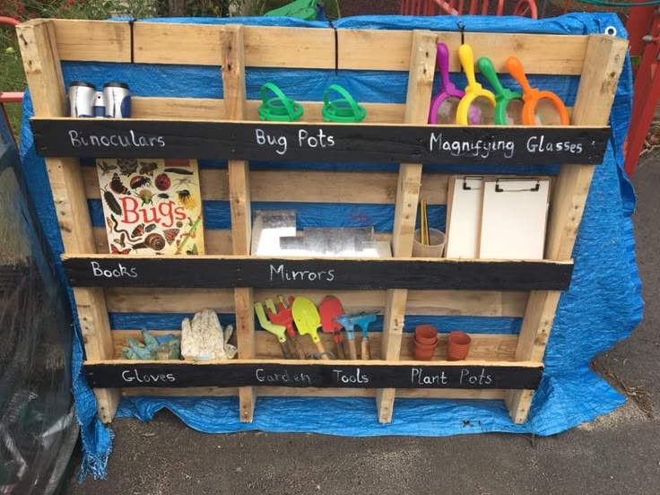 a wooden shelf filled with lots of different types of crafting supplies on top of a blue tarp