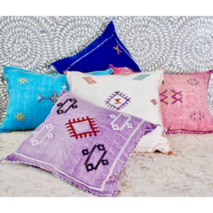 four colorful pillows sitting on top of a bed