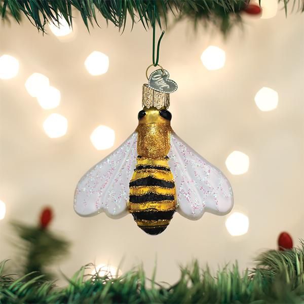 a glass ornament shaped like a bee hanging from a christmas tree with lights in the background