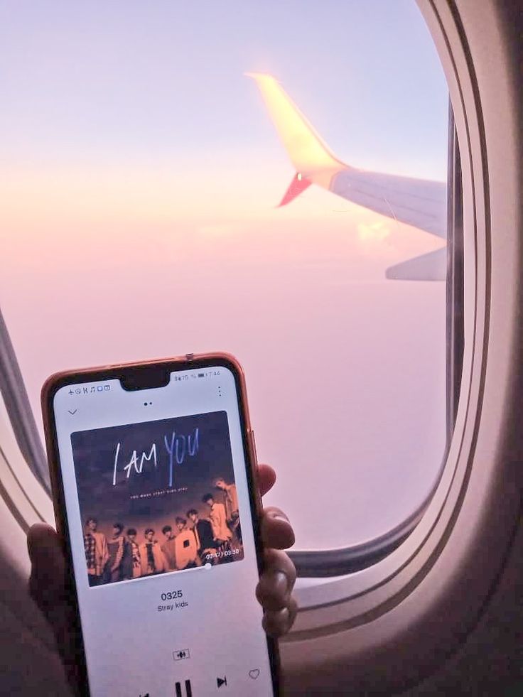 someone holding up their cell phone in front of an airplane window