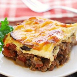 a piece of lasagna on a plate with parsley and fork in the background