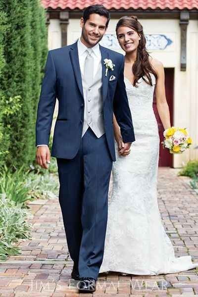 a bride and groom holding hands walking down a brick path in front of a building