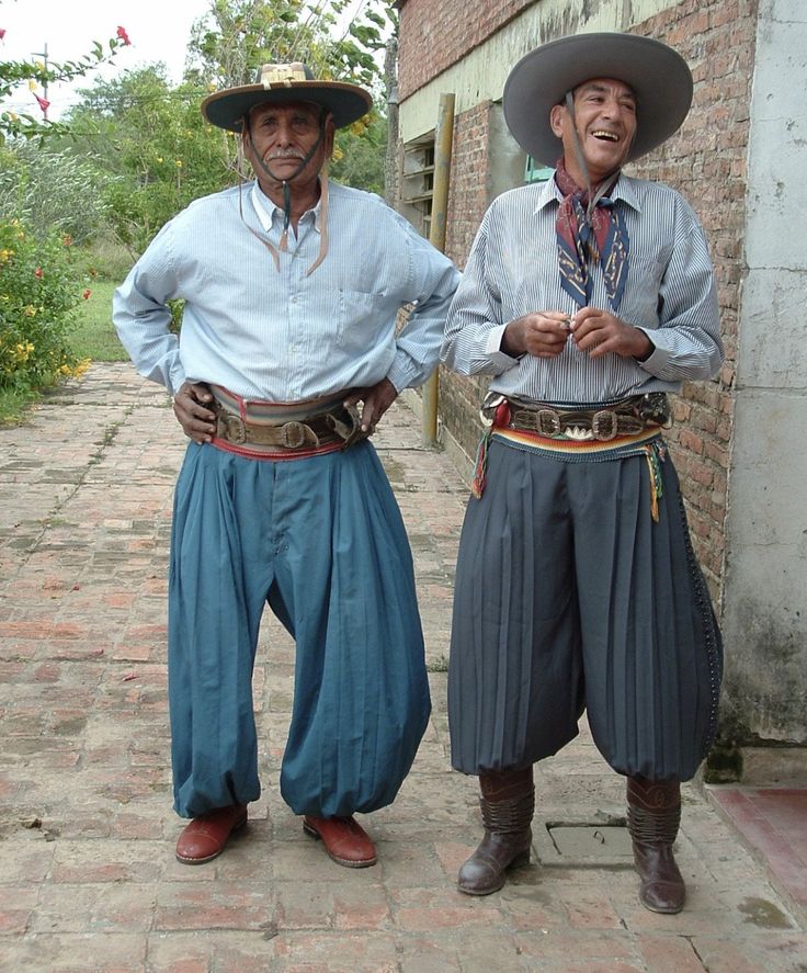 two men in traditional mexican garb standing next to each other on a brick walkway