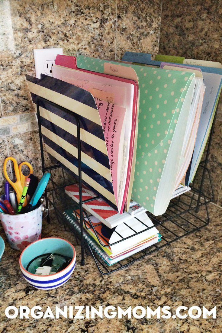 an organized desk with binders, pens, and scissors on the counter in front of a marble wall