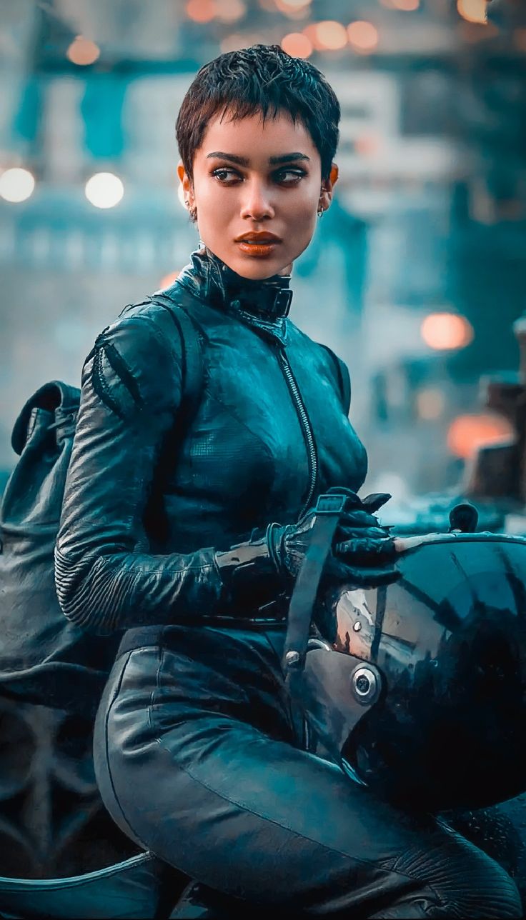 a woman sitting on top of a motorcycle in black leathers and gloves with her hands behind her back