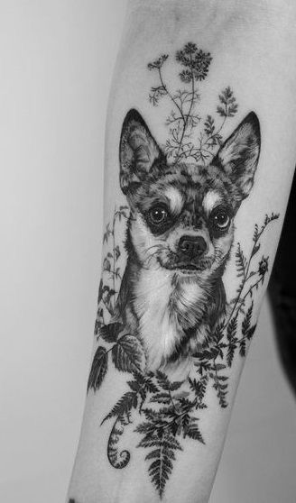 a black and white photo of a dog with flowers on it's arm,