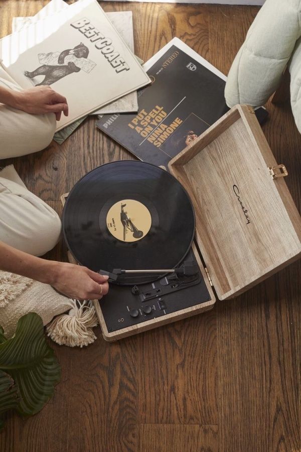 a woman sitting on the floor next to an old record player and other items that have been placed around her